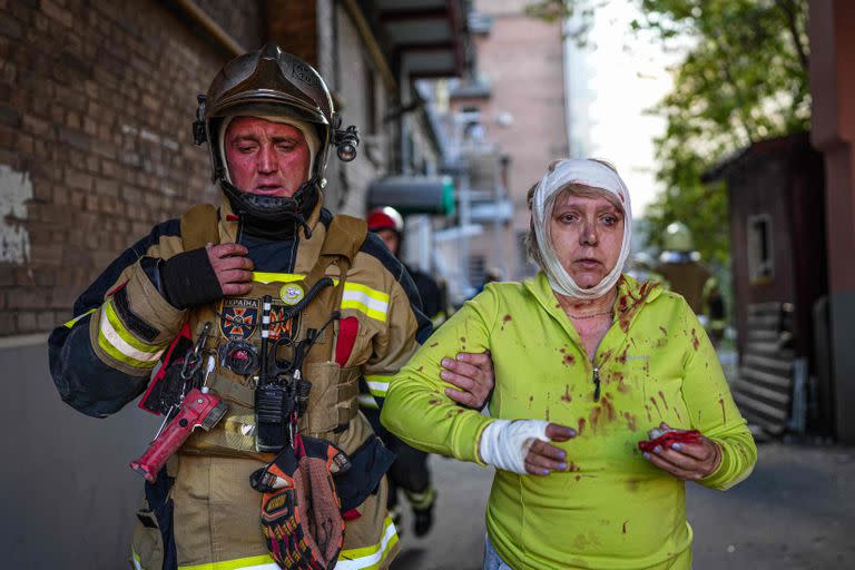 Esta foto difundida por el Servicio Estatal de Emergencias de Ucrania el 10 de octubre de 2022 muestra a un rescatista ayudando a una mujer herida después de que varios ataques golpearan la capital ucraniana de Kiev, en medio de la invasión rusa de Ucrania.