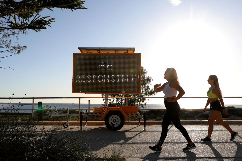 Members of the public are seen walking past a sign asking them to 'Be Responsible' at Scarborough Beach, Perth. Source: AAP