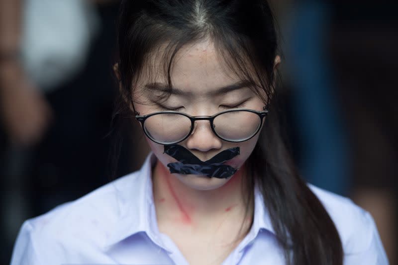 Nalinrat Tuthubthim, 20, a student, who claims she was sexually abused by a teacher, has her mouth covered with tape during a rally in Bangkok