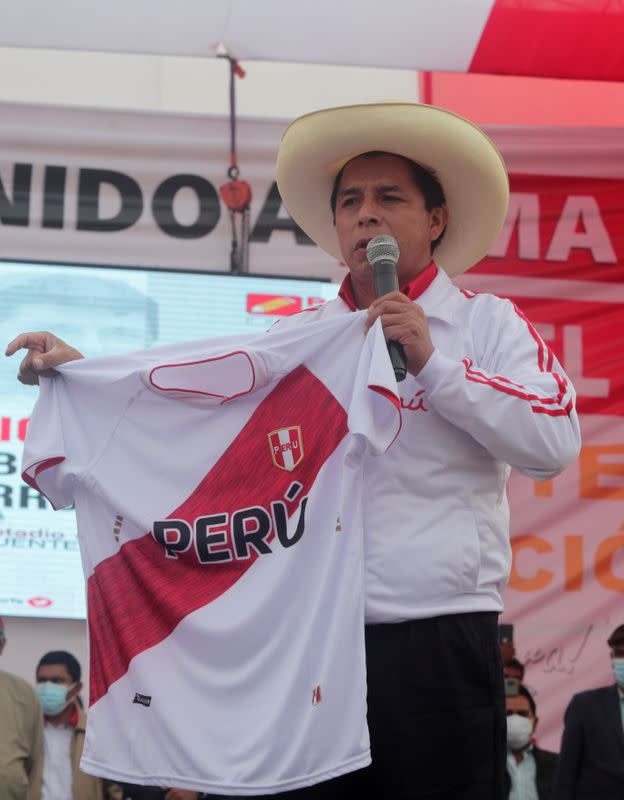 El candidato presidencial Pedro Castillo sostiene una camiseta de la selección peruana de fútbol durante un mitin en Lima, Perú