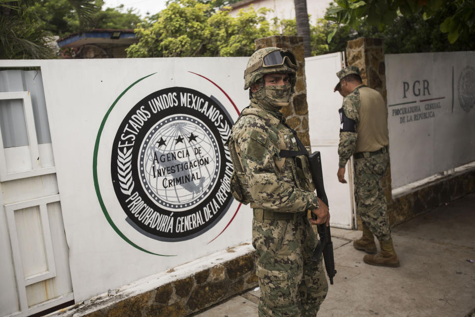 A marine, front, and National Guard, behind, stand guard outside an office of the General Attorney where migrants are brought before being transferred to Tapachula from Arriaga, Mexico, Sunday, June 23, 2019. Mexico has completed its deployment of 6,000 National Guard agents to help control the flow of migrants headed toward the U.S. and filled immigration agency posts to regulate border crossings, the government said Friday. (AP Photo/Oliver de Ros)