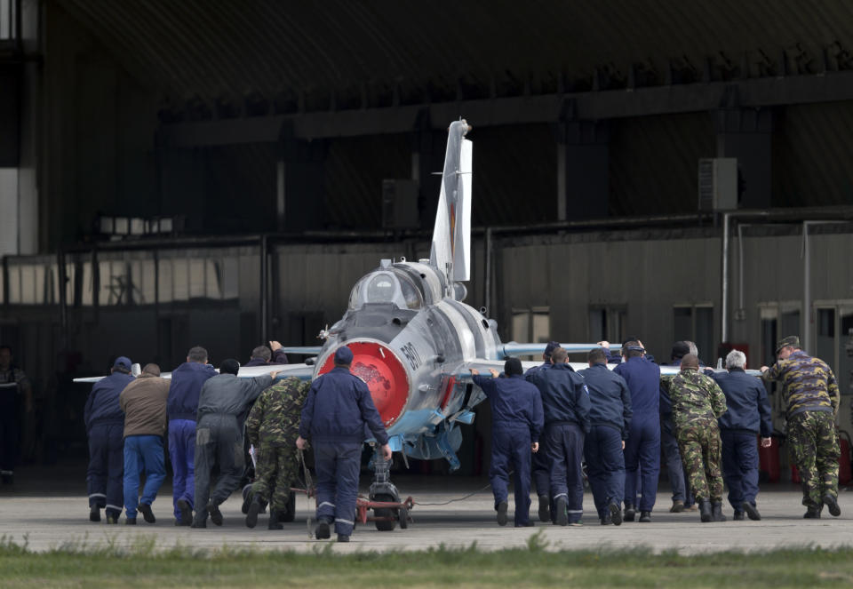 FILE - In this Thursday, April 10, 2014 file picture, Romanian air force employees push a MIG 21 Lancer fighter jet in Campia Turzii, Romania. The U.S. Air Force has deployed on Monday, Jan. 4, 2021, about 90 airmen and an unspecified number of drone aircraft to a base in central Romania, boosting its military presence in the region where there are allied concerns that Russia is trying to display its military strength. (AP Photo/Vadim Ghirda, File)