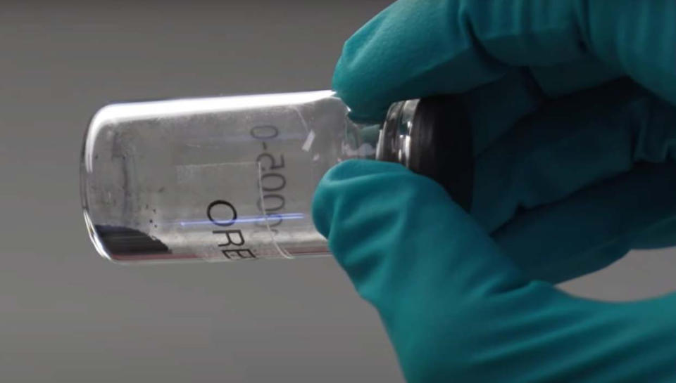 gray powder and tiny rocks in a glass bottle