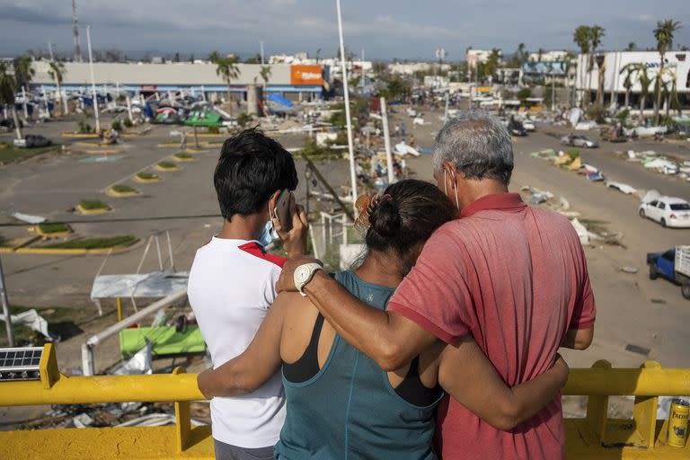 Residentes, parados en un paso elevado, observan los daños causados por el huracán Otis en Acapulco