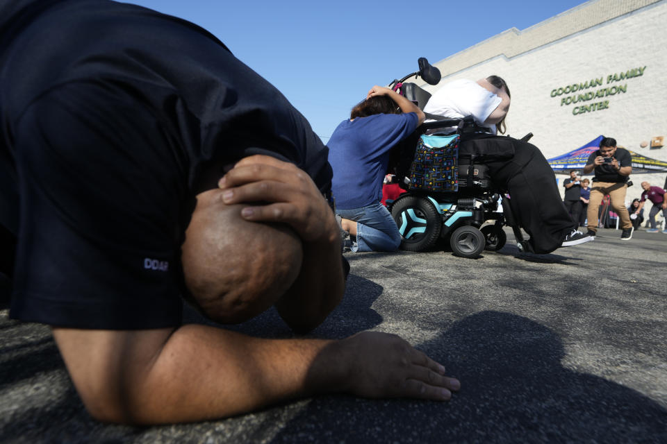 Workers practice "drop, cover, and hold on" during an after shock simulation at a ShakeOut earthquake drill at the Los Angeles Regional Food Bank in Los Angeles Thursday, Oct. 19, 2023. Up and down the West Coast, the ShakeOut drill was scheduled to begin at 10:19 a.m. PDT with a cellphone-rattling test alert from the region's ShakeAlert earthquake warning system.(AP Photo/Damian Dovarganes)