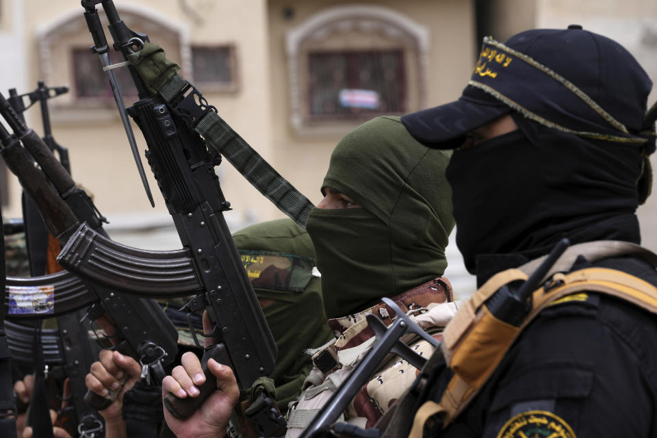 Masked members of the Al-Quds Brigades, the military wing of the Islamic Jihad group, hold their weapons during a rally celebrating the last night shooting rampage in Israel in which a Palestinian attacker killed two Israelis after Friday prayer outside the main mosque in Khan Younis City, southern Gaza Strip, Friday, April 8, 2022. (AP Photo/Adel Hana)