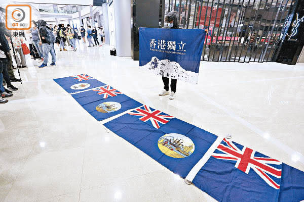黑衣人展示港獨旗，又將港英旗鋪在地面。（何天成攝）