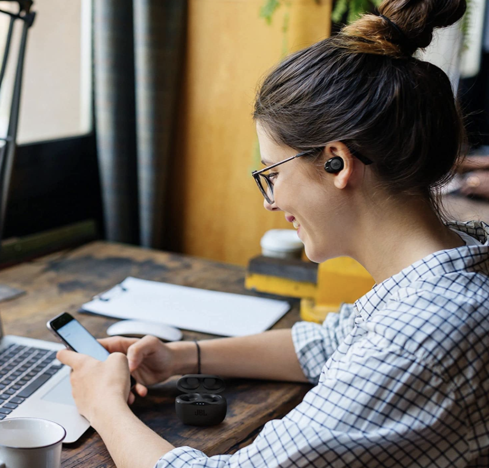 woman sitting at desk with laptop and JBL Tune 125TWS True Wireless In-Ear Bluetooth Headphones (Photo via Amazon)