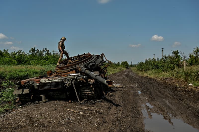 Ukrainian serviceman inspects a destroyed Russian tank is seen in the recently liberated village of Novodarivka