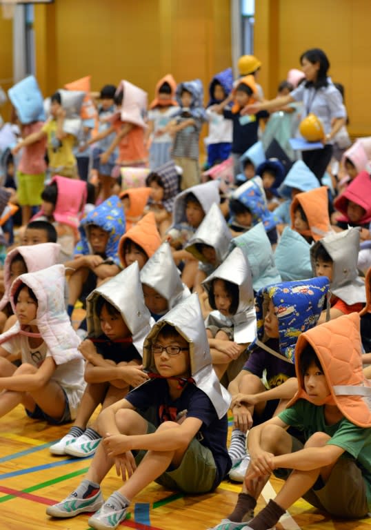 Elementary school children wear fireproof hoods as they gather at a hall during an earthquake drill at a school in Tokyo, on September 1, 2015