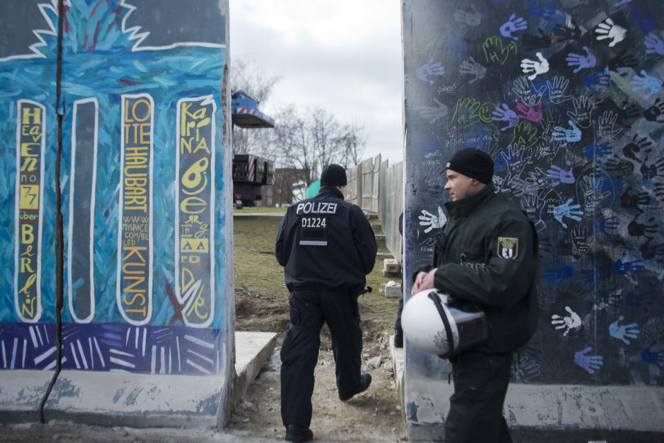 German police officers protect a part of the former Berlin Wall in Berlin, Germany, Friday, March 1, 2013. Construction crews stopped work Friday on removing a small section from one of the few remaining stretches of the Berlin Wall to make way for a condo project after hundreds of protesters blocked their path. (AP Photo/Markus Schreiber)