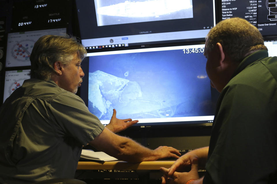 In this Wednesday, Oct. 16, 2019 photo, Vulcan Inc. director of undersea operations for the Petrel, Rob Kraft, left, and the Naval History and Heritage Command's Frank Thompson, left, look at footage of the Japanese aircraft carrier Kaga, off Midway Atoll in the Northwestern Hawaiian Islands. Deep-sea explorers scouring the world's oceans for sunken World War II ships are honing in on a debris field deep in the Pacific. The research vessel called the Petrel is launching underwater robots about halfway between the U.S. and Japan in search of warships from the Battle of Midway. (AP Photo/Caleb Jones)