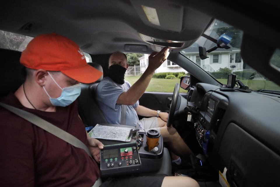 Chris Gagnon, center, field operations manager for the East Middlesex Mosquito Control Project, prepares to spray to control mosquitos from a pick-up truck with co-worker Peter Mirata, left, on Wednesday, July 8, 2020, while driving through a neighborhood in Burlington, Mass. Officials are preparing for another summer with a high number of cases of eastern equine encephalitis, a rare but severe neurological illness transmitted by mosquitoes that hit the state particularly hard last summer. (AP Photo/Charles Krupa)