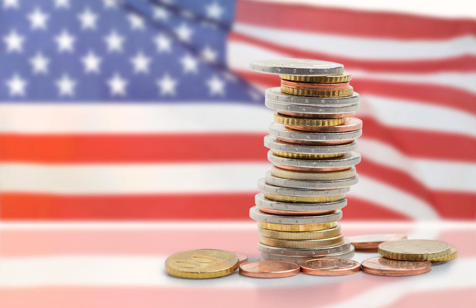 A stack of coins sitting in front of an American flag.