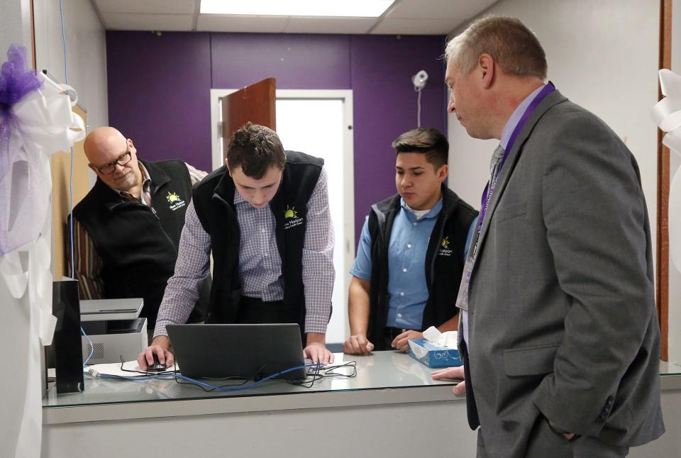 With help from New Horizon CEO Michael Heidenreich, left, Barberton seniors Aaron George, center, and Miguel Guerrero open a savings account for Principal Henry Muren at New Horizon Federal Credit Union inside Barberton High School on Tuesday.