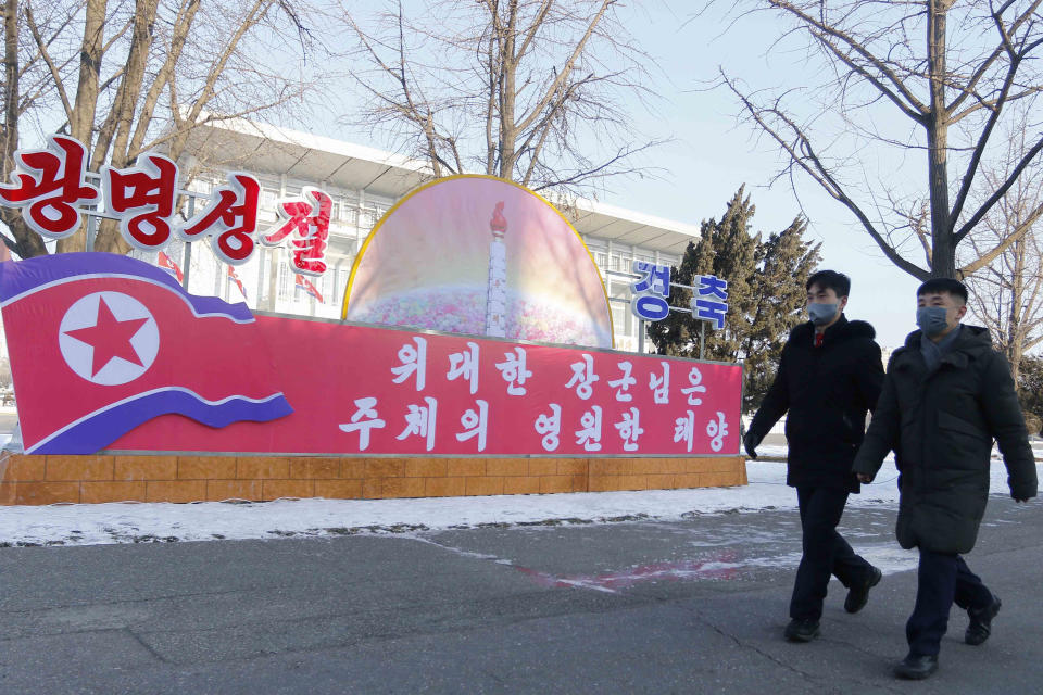 Citizens walk past a celebrative poster in Pyongyang, North Korea on the occasion of the 80th birth anniversary of the country's late leader Kim Jong Il, Wednesday, Feb. 16, 2022. The letters in the poster read " Great General is the Eternal Sun of Juche." (AP Photo/Jon Chol Jin)