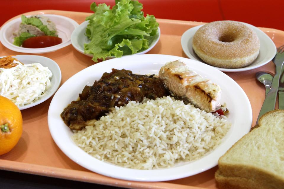 A school lunch consisting of rice, salmon, ratatouille, a slice of bread, a salad with celery and carrots, and an orange and donut is laid out on a tray at the Anne Franck school in Lambersart, northern France, Tuesday, May 6, 2014. (AP Photo/Michel Spingler)