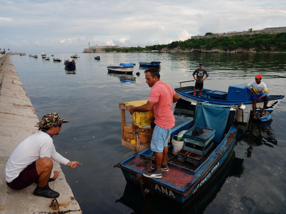 fisherman move small boats in a line along the water