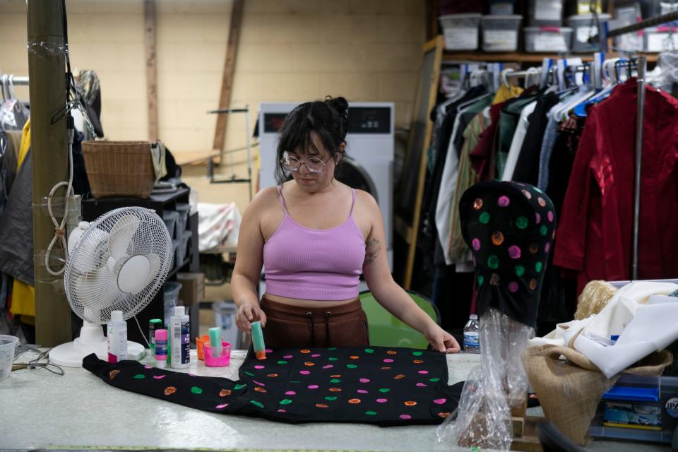 Actress Lauren Wagner, of El Paso, Texas, applies painted neon dots to a black shirt for a costume, which be used in the polka dot room on the haunted trail, inside of the costume shop preparing for the upcoming "It's Alive" production at Haunted Mountain on September 21, 2023, in Chillicothe, Ohio.