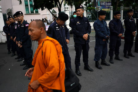 Police officers stand guard as a buddhist monk walks past near a university where anti-government protesters gather to demand that the military government hold a general election by November, in Bangkok, Thailand, May 22, 2018. REUTERS/Athit Perawongmetha