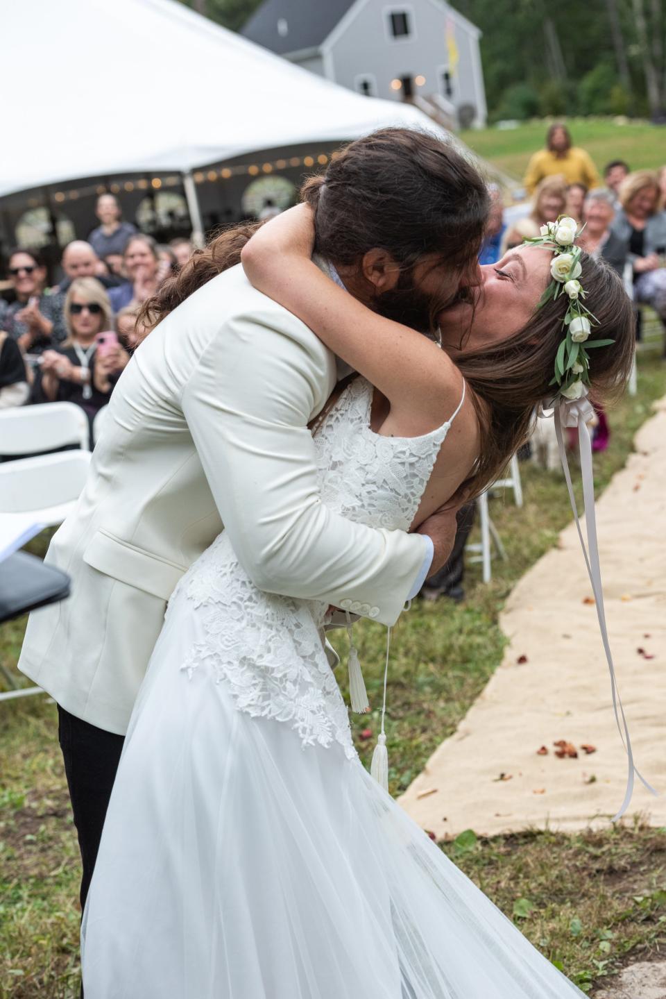 Anthony and Kelly Anne Ferraro kiss at their wedding in October as their guests applaud.