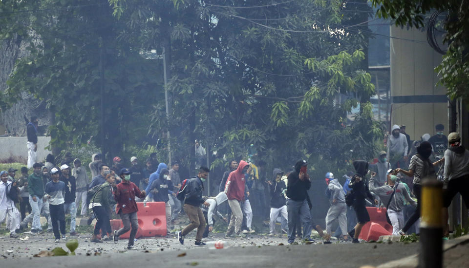 Student protester throws rock at riot police officers during a clash in Jakarta, Indonesia, Monday, Sept. 30, 2019. Thousands of Indonesian students resumed protests on Monday against a new law they say has crippled the country's anti-corruption agency, with some clashing with police.(AP Photo/Achmad Ibrahim)