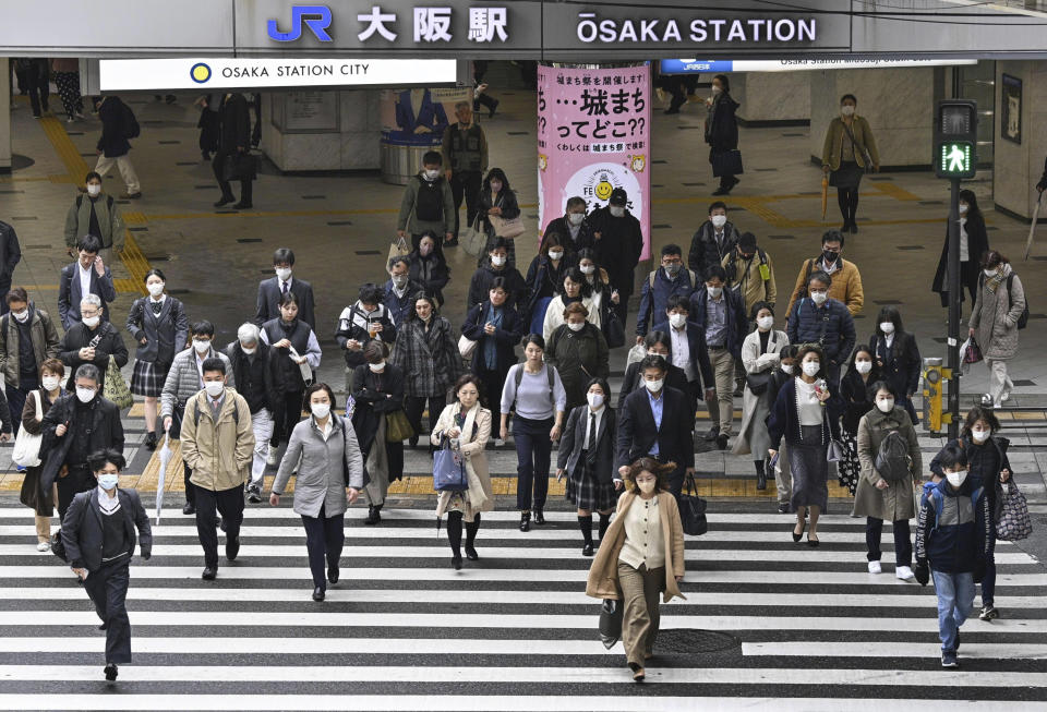 People walk across an intersection in Osaka, western Japan, Monday, March 13, 2023. Japan is dropping its mask wearing request beginning Monday for the first time in three years as the country further eases COVID-19 rules in public places and tries to expand business and other activity. (Yu Nakajima/Kyodo News via AP)