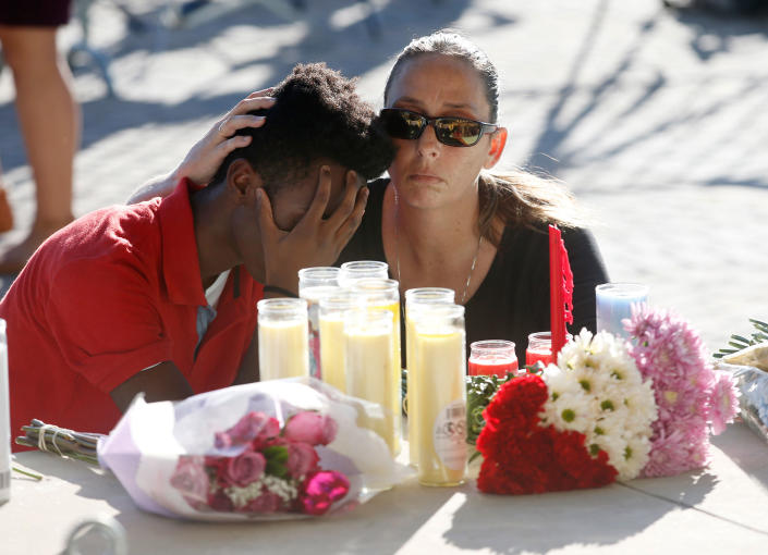 <p>Pamela Tilton, right, comforts Che James-Riley, 18, as they light a candle at a memorial for the victims of the shooting at Marjory Stoneman Douglas High School, Thursday, Feb. 15, 2018, in Parkland, Fla. Tilton, a swimming coach and swimmer James-Riley at Coral Lakes High School, competed against one of the victims. (Photo: Wilfredo Lee/AP) </p>