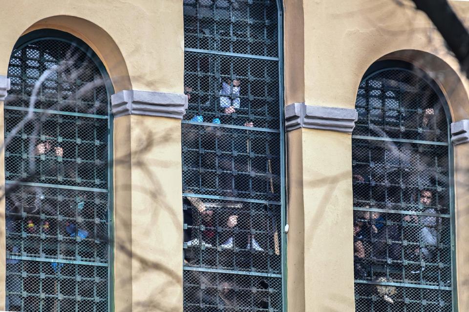 Inmates hang on to bars behind windows of a wing as they stage a protest at the San Vittore prison in Milan on March 9, 2020, in one of Italy's quarantine red zones. - Inmates in four Italian prisons have revolted over new rules introduced to contain the coronavirus outbreak, leaving one prisoner dead and others injured, a prison rights group said on March 8. Prisoners at jails in Naples Poggioreale in the south, Modena in the north, Frosinone in central Italy and at Alexandria in the northwest had all revolted over measures including a ban on family visits, unions said. (Photo by Miguel MEDINA / AFP) (Photo by MIGUEL MEDINA/AFP via Getty Images)