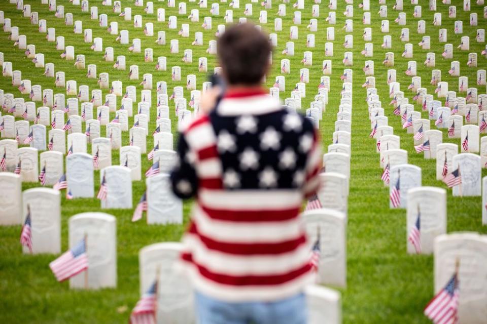 A man wearing a flag-adorned sweater, stops to take a picture on Memorial Day at the Los Angeles National Cemetery.