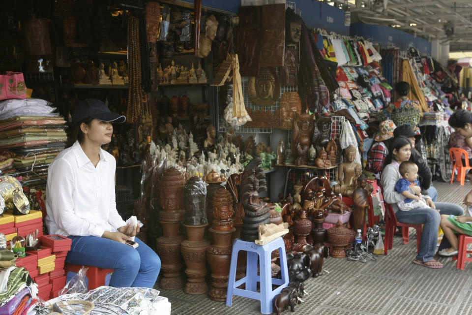 In this Wednesday, Feb. 27, 2013, a Cambodian vendor selling home goods waits for customers at the Central Market (Phsar Thum They) in Phnom Penh, Cambodia. Beneath a lemon-yellow art deco dome, the Central Market offers miles of no-strings-attached window-shopping. But if you can't stand the thought of leaving empty-handed, pick up flip-flops, jewelry, delicacies like juicy mangosteen fruit or fried insects, or khama scarves in bright, gingham-like patterns. (AP Photo/Heng Sinith)