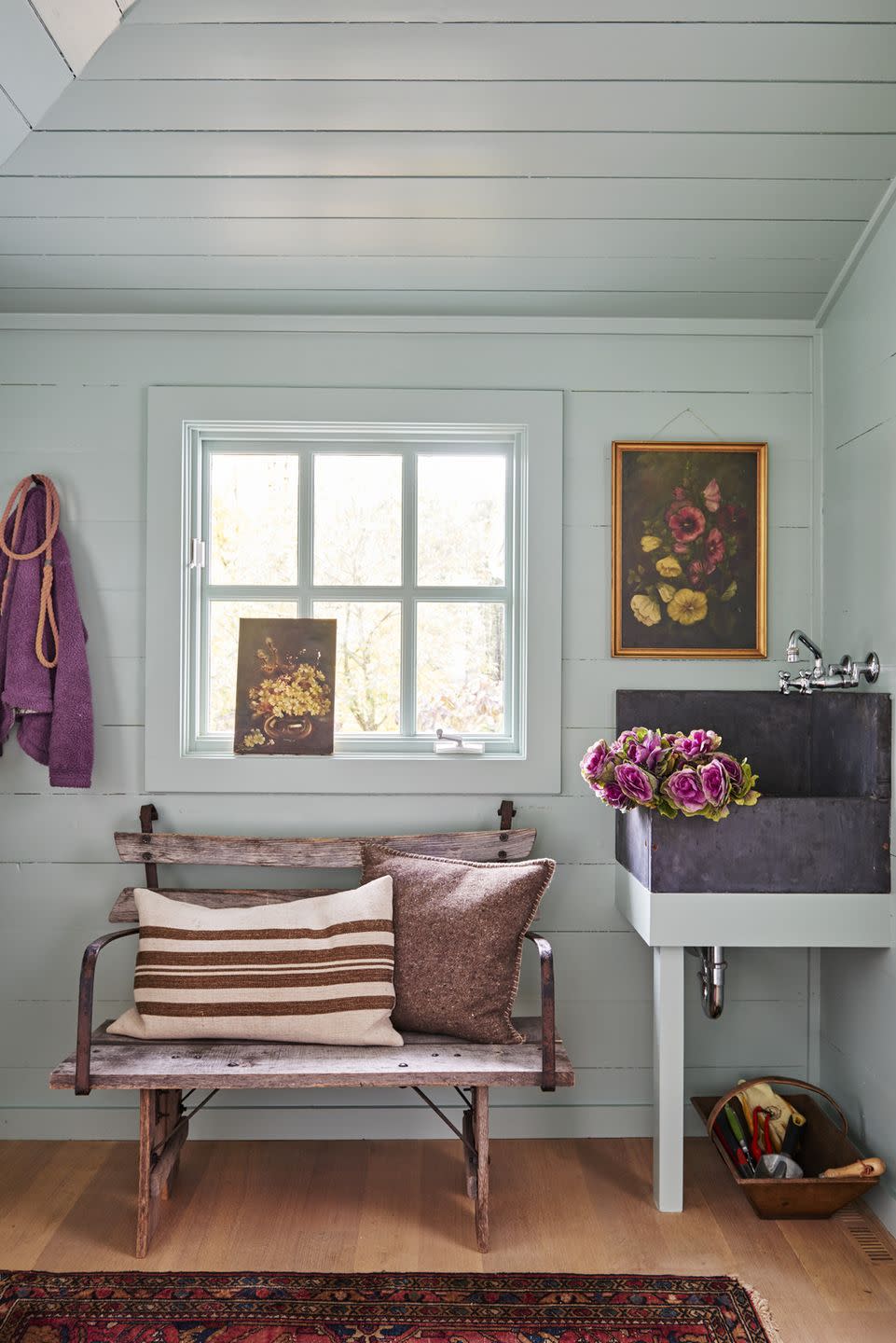 a mudroom room with a bench and a window, flowers in a nearby sink