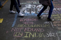 Protesters walk over a graffiti on the ground against the new citizenship law during a protest at Jantar Mantar near the Indian parliament in New Delhi, India, Thursday, Dec. 19, 2019. Police detained several hundred protestors in some of India's biggest cities Thursday as they defied a ban on assembly that authorities imposed to stem widespread demonstrations against a new citizenship law that opponents say threatens India's secular democracy. Dozens of demonstrations were to take place around country as opposition grows to a new citizenship law that excludes Muslims. The law has sparked anger at what many see as the government's push to bring India closer to a Hindu state. (AP Photo/Altaf Qadri)