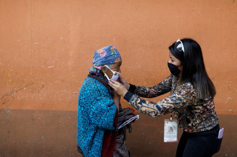 A municipal worker adjusts a face mask on a woman on the street amid the outbreak of the coronavirus disease (COVID-19), in Totonicapan