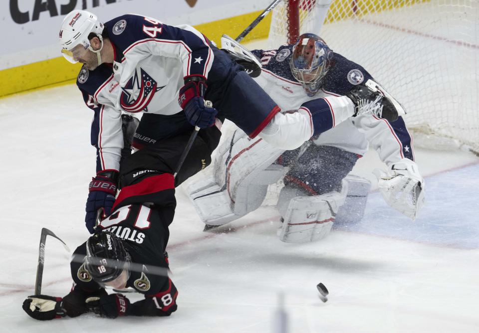 Ottawa Senators center Tim Stutzle gets tied up with Columbus Blue Jackets defenseman Erik Gudbranson as goaltender Daniil Tarasov keeps an eye on the puck during the third period of an NHL hockey game, Tuesday, Feb. 13, 2024, in Ottawa, Ontario. (Adrian Wyld/The Canadian Press via AP)