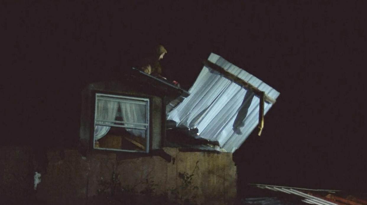 An emergency worker moves debris on top of damaged house early Wednesday, Dec. 14, 2022 in Caddo Parish, Louisiana. ,A destructive storm marched across the United States, spawning tornadoes that touched down in parts of Texas, Oklahoma and Louisiana, where two deaths were reported, and it delivered blizzard-like conditions to the Great Plains and threatened more severe weather Wednesday in the South. (KSLA via AP)