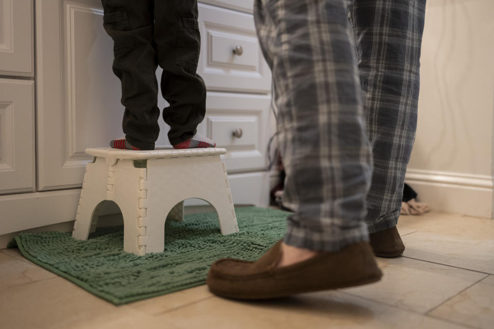 Ethan Quinn, 4, stands on a stool to brush his teeth as his father, Scott, watches while getting ready for his daycare center in Concord, Calif., Wednesday, Nov. 1, 2023. (AP Photo/Jae C. Hong)