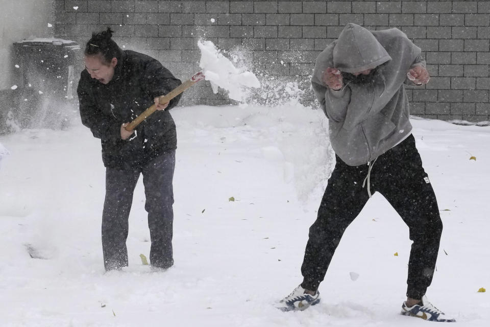 Residents play with fresh snow in Beijing, China, Sunday, Nov. 7, 2021. An early-season snowstorm has blanketed much of northern China including the capital Beijing, prompting road closures and flight cancellations. (AP Photo/Ng Han Guan)