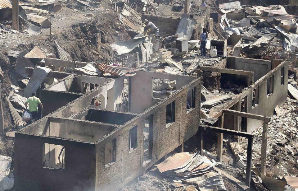 Residents attempt to salvage belongings from houses after a forest fire burned several neighbourhoods in the hills in Valparaiso city