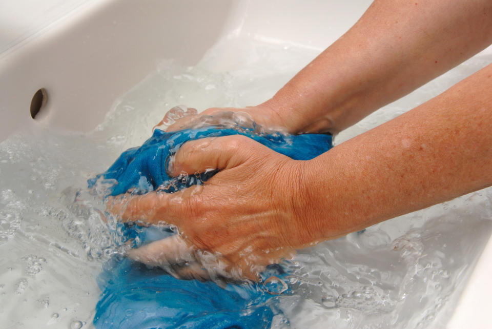 a person handwashing clothing in a sink