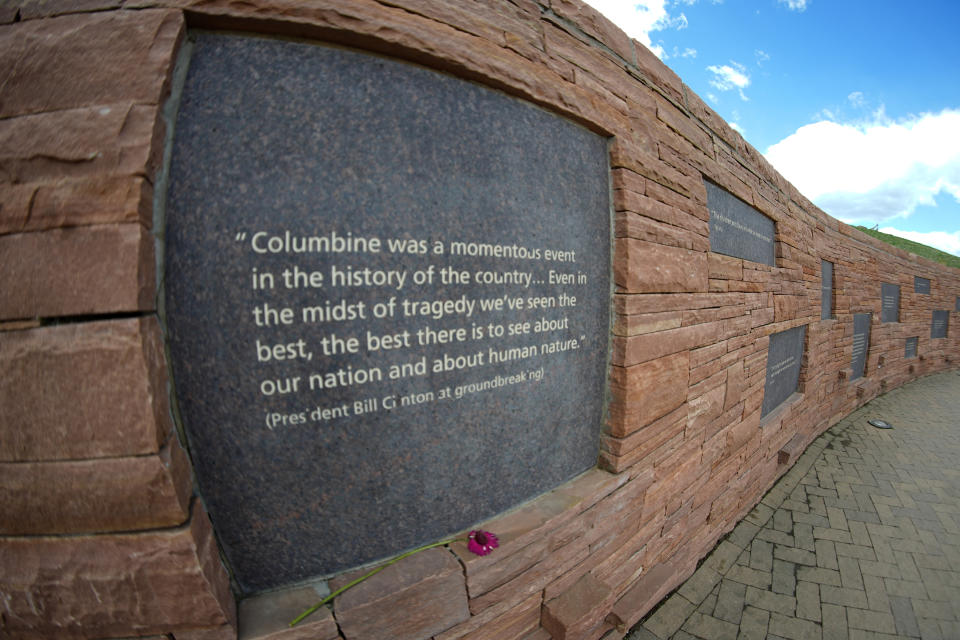 In this view through a fisheye lens, a plaque with a quote from President Bill Clinton is displayed on the wall of healing at the Columbine Memorial Wednesday, April 17, 2024, in Littleton, Colo. Trauma still shadows the survivors of the horrific Columbine High School shooting as the attack's 25th anniversary approaches. (AP Photo/David Zalubowski)