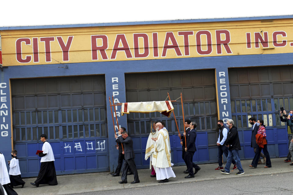 Archbishop Alexander Sample carries the Eucharist down Northwest Everett Street past a radiator shop in Portland, Ore., on the way to lead a rosary and exorcism for peace and justice in the city on Oct. 17, 2020. In popular culture, exorcism often serves as a plot device in chilling films about demonic possession. Recently, two Roman Catholic archbishops showed a different face of exorcism. They performed the rite in well-attended outdoor ceremonies to drive out any evil spirits lingering after acrimonious protests. In Portland, Oregon, Archbishop Alexander Sample led a procession of more than 200 people to a city park, then conducted an exorcism rite. The event followed more than four months of racial-justice protests in Portland. (Ed Langlois/Catholic Sentinel via AP)