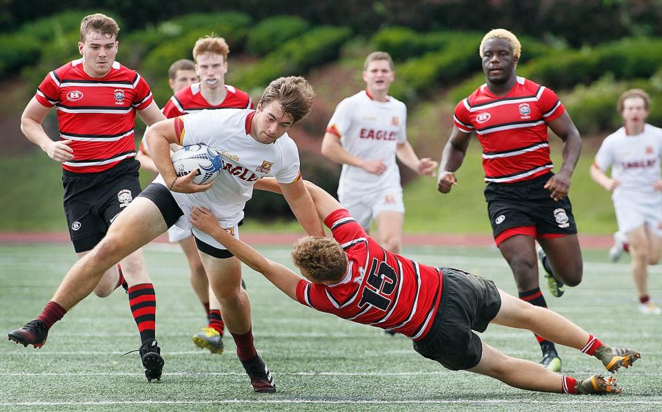 Eagle Jack McNicholl tries to break a Milton tackle by Evan Johnson as Milton hosts Boston College High in MIAA rugby on Thursday, July 1, 2021.