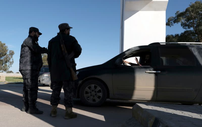 Policemen stand near a gate at the western entrance to the city of Benghazi