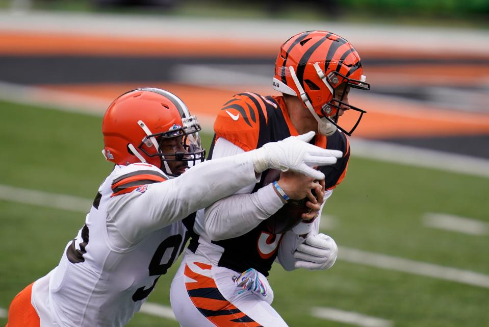 Cincinnati Bengals quarterback Joe Burrow, right, is sacked by Cleveland Browns' Myles Garrett (95) during the first half of an NFL football game, Sunday, Oct. 25, 2020, in Cincinnati. (AP Photo/Michael Conroy)