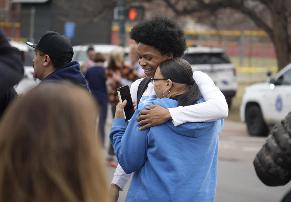 A student, rear, hugs a woman as they reunite following a shooting at East High School, Wednesday, March 22, 2023, in Denver. Authorities say two school administrators were shot and wounded after a handgun was found during a daily search of a student at the Denver high school. (AP Photo/David Zalubowski)