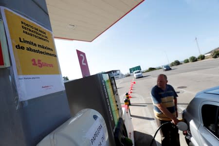 A placard reading "Maximum limit 15 litres per filling" is seen as a man fills up a car during a fuel strike, at a gas station in Lisbon