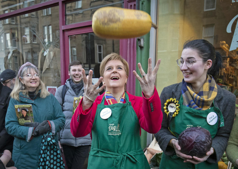 SNP leader Nicola Sturgeon, centre and SNP candidate for Edinburgh South Catriona MacDonald, right, pose for a photo, during a visit to Digin Community Greengrocer in Edinburgh, Scotland, on the last day of the General Election campaign trail, Wednesday, Dec. 11, 2019. Britain goes to the polls on Dec. 12. (Jane Barlow/PA via AP)