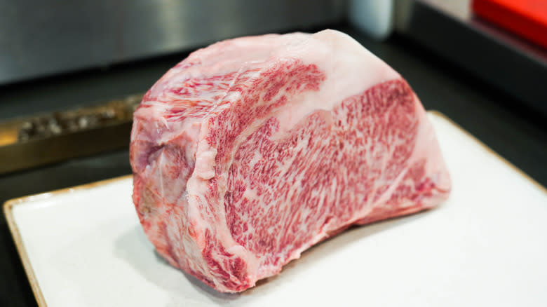 Raw whole A5 Wagyu ribeye on white cutting board