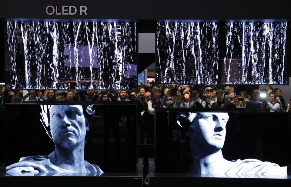 People take pictures of a display of LG Signature OLED R TVs at the LG booth during the CES tech show, Tuesday, Jan. 7, 2020, in Las Vegas. (AP Photo/John Locher)